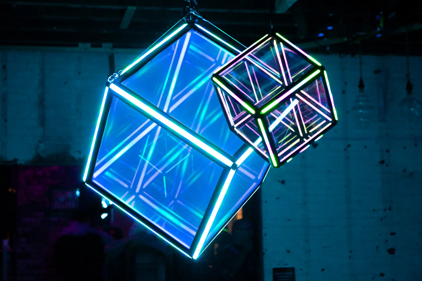 Two illuminated cubes suspended in darkness, one glowing solid blue, the other an open wireframe outline.